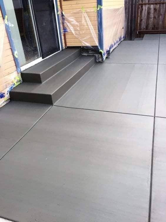 Freshly poured concrete patio with matching steps leading to a sliding glass door