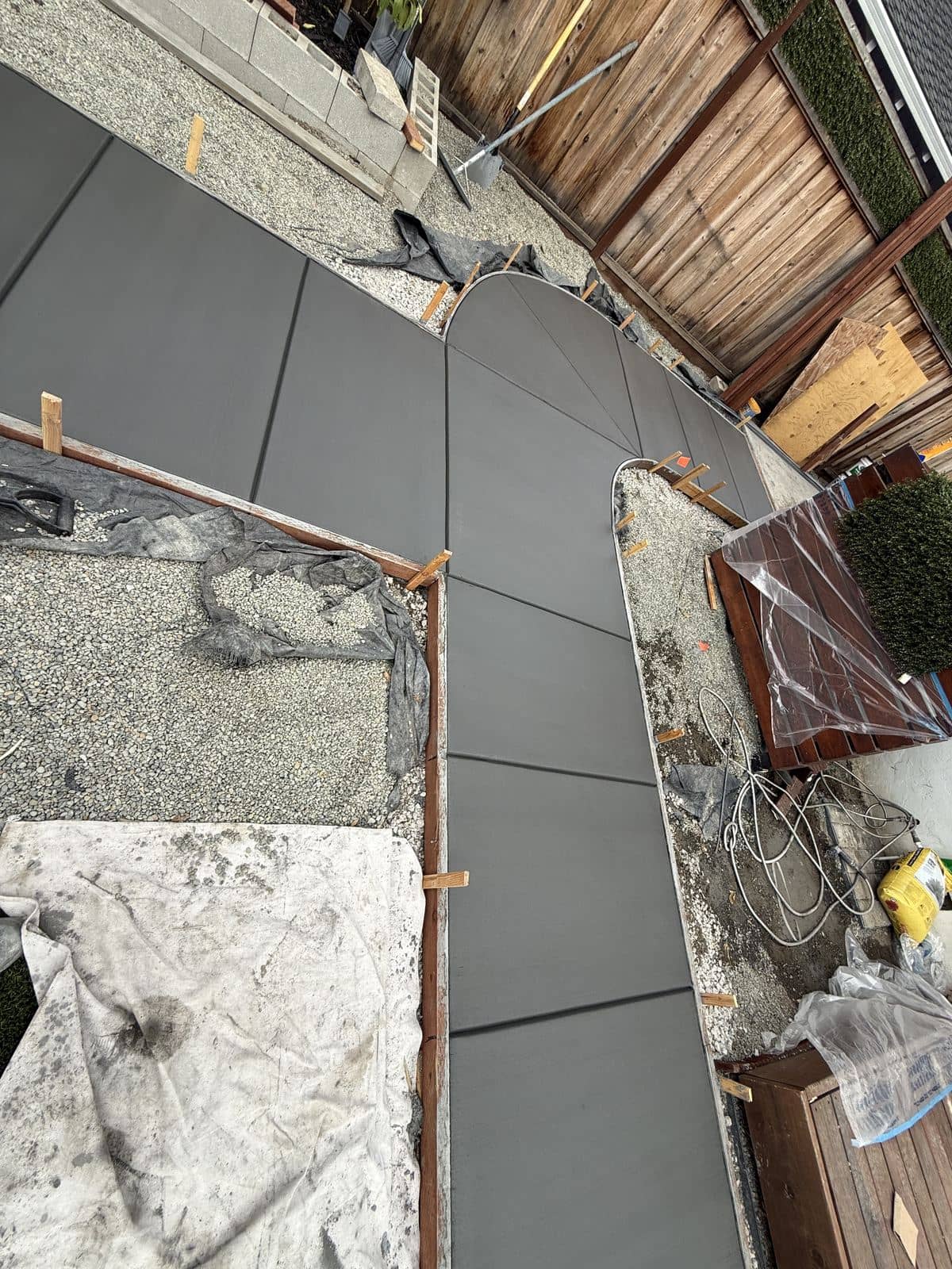 Close-up of a freshly poured concrete walkway with a curved edge and control joints