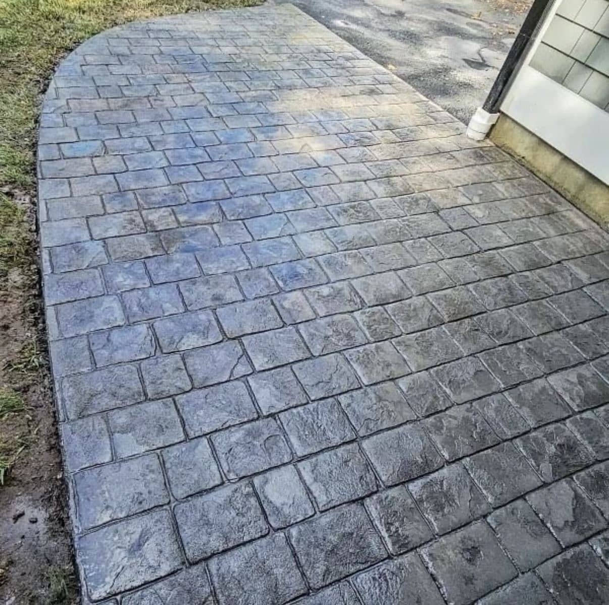 Stamped concrete walkway in a blue-gray cobblestone pattern leading to a side door