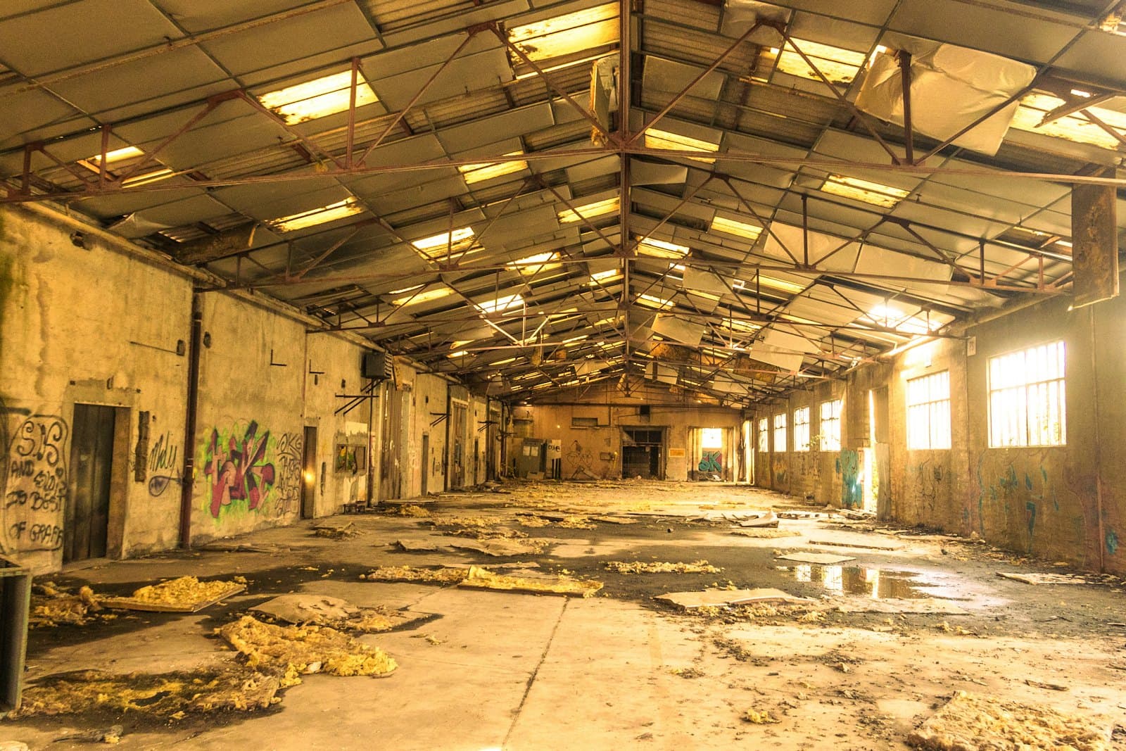Deteriorated warehouse interior with a broken, debris-covered floor slab