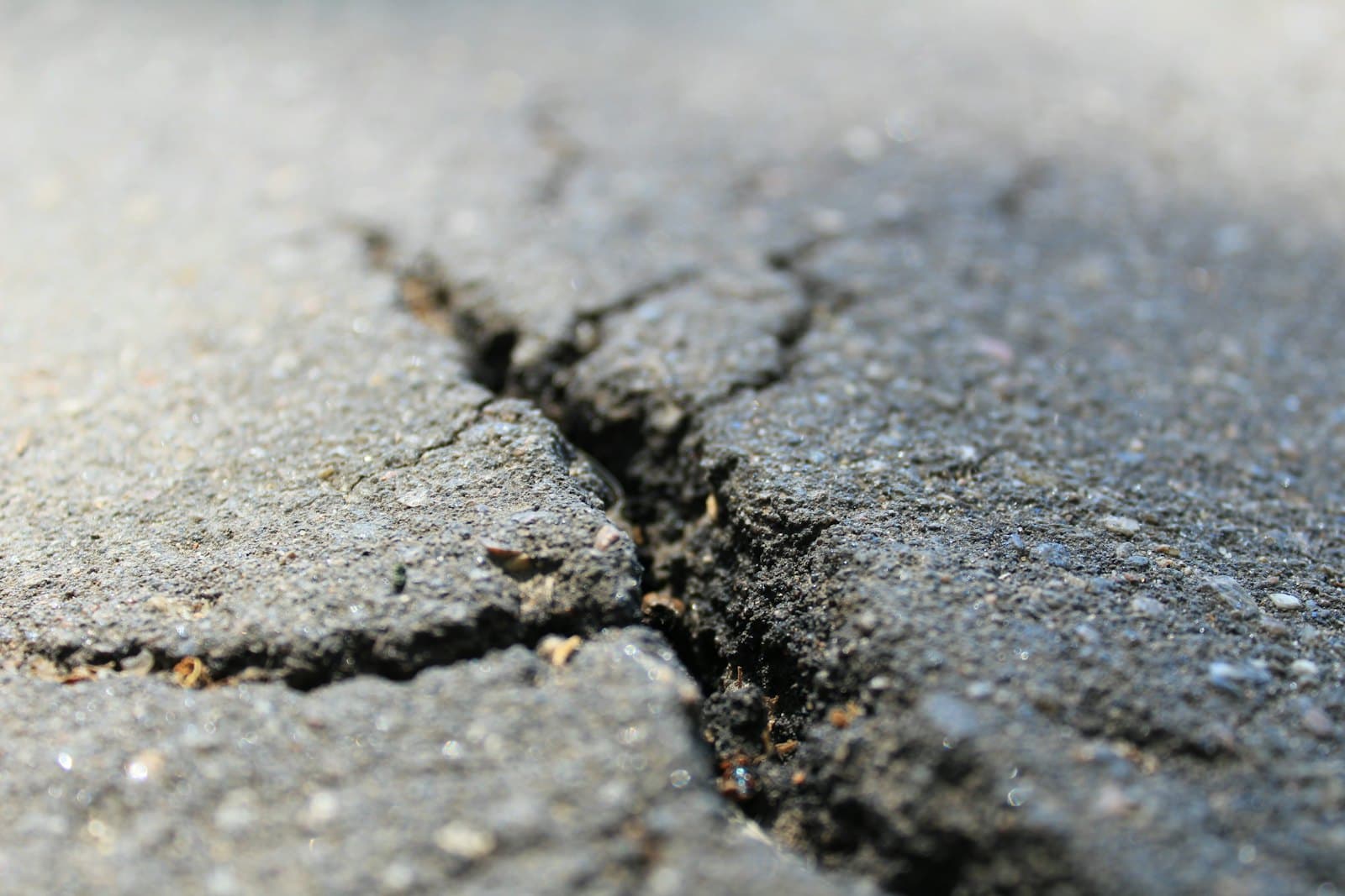 Long fatigue crack running through worn, patched parking area pavement