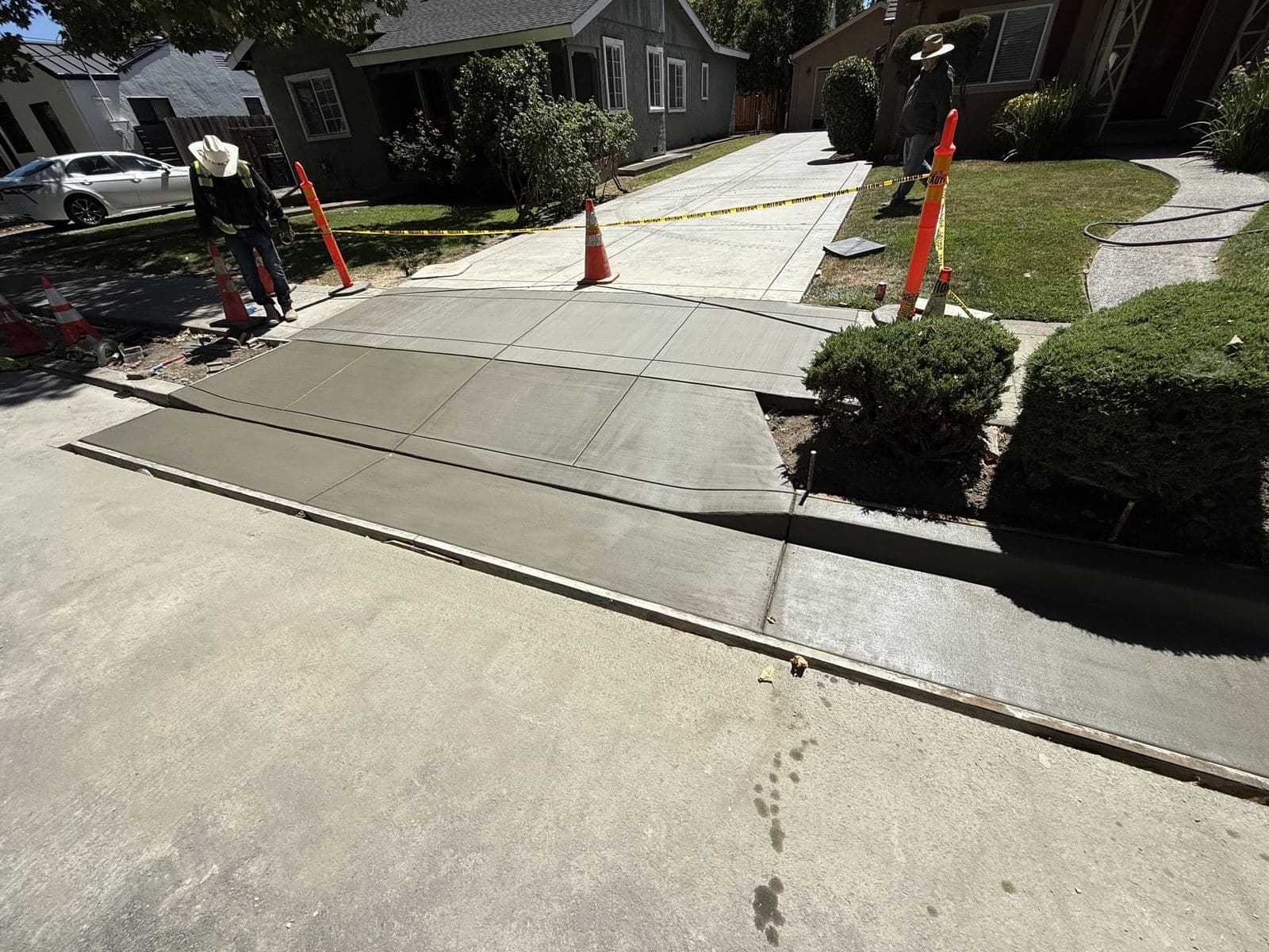 New concrete driveway apron and sidewalk approach curing behind caution tape