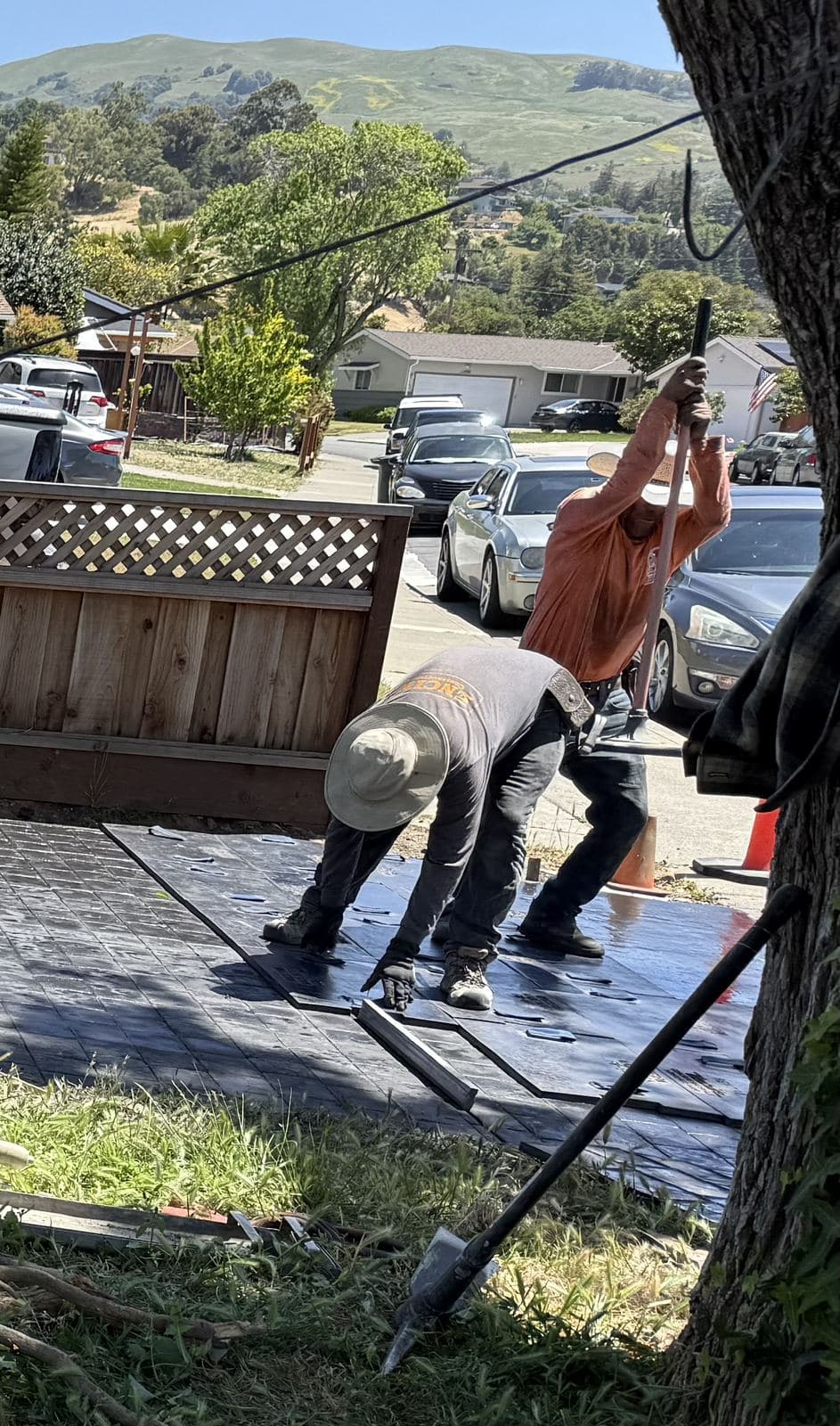 Concrete crew laying textured stamping mats onto a fresh driveway pour