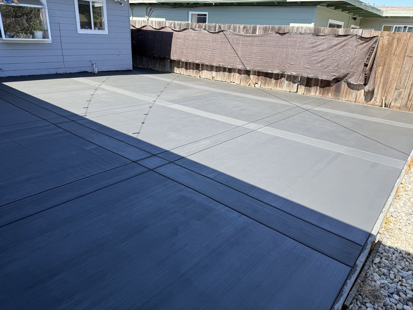 Large backyard concrete patio with a broom finish and a banded border pattern