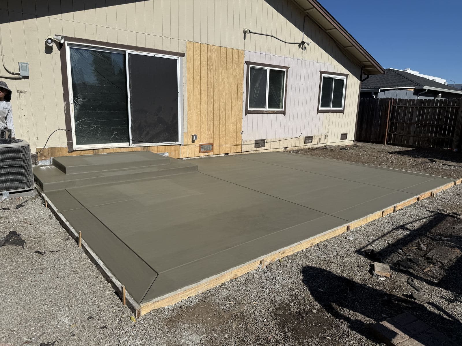 Wide view of a freshly poured concrete patio and steps behind a home