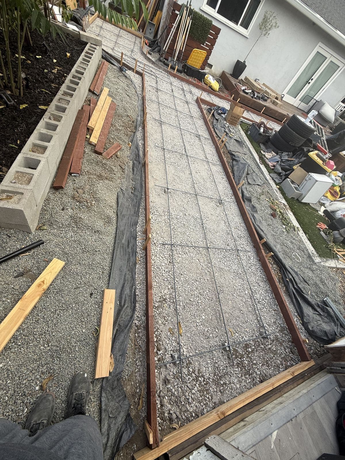 Rebar mesh laid over a compacted gravel base ahead of a walkway pour