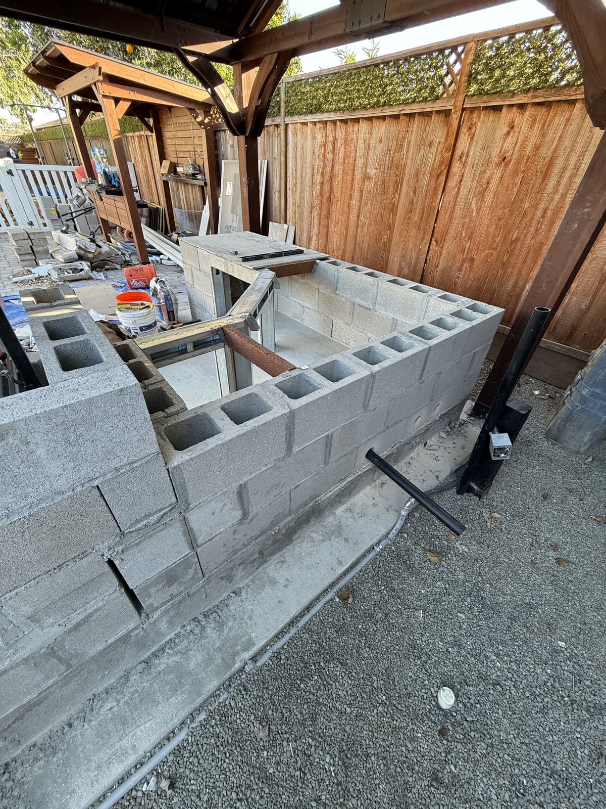 Outdoor kitchen block walls being built against a wood fence