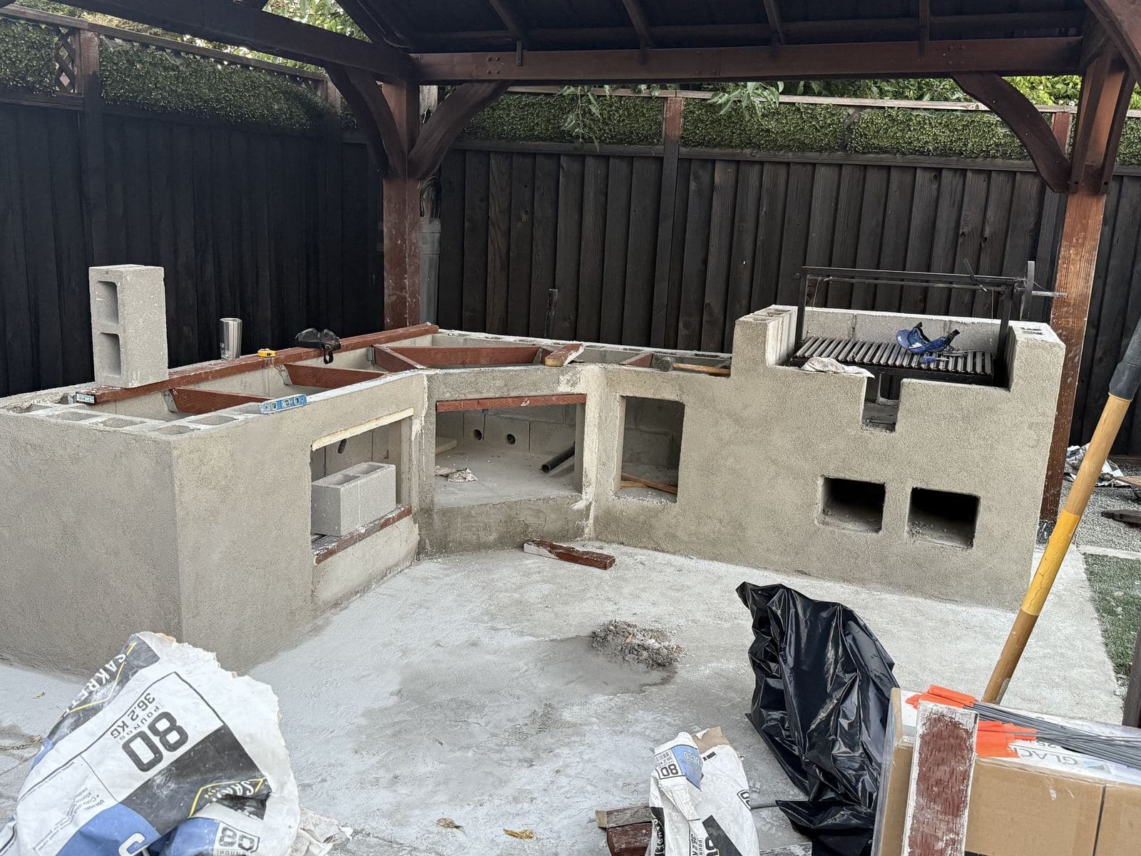 Wide view of an outdoor kitchen island with scratch-coat stucco and a built-in grill