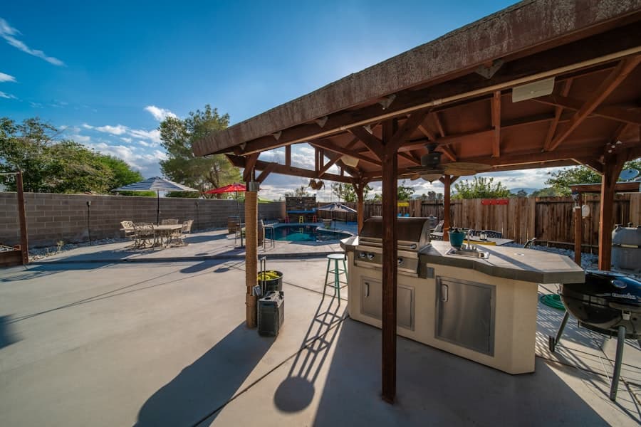 Covered concrete patio featuring a grill and outdoor dining table