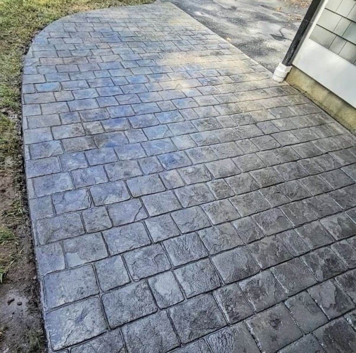 Stamped concrete walkway in a blue-gray cobblestone pattern leading to a side door
