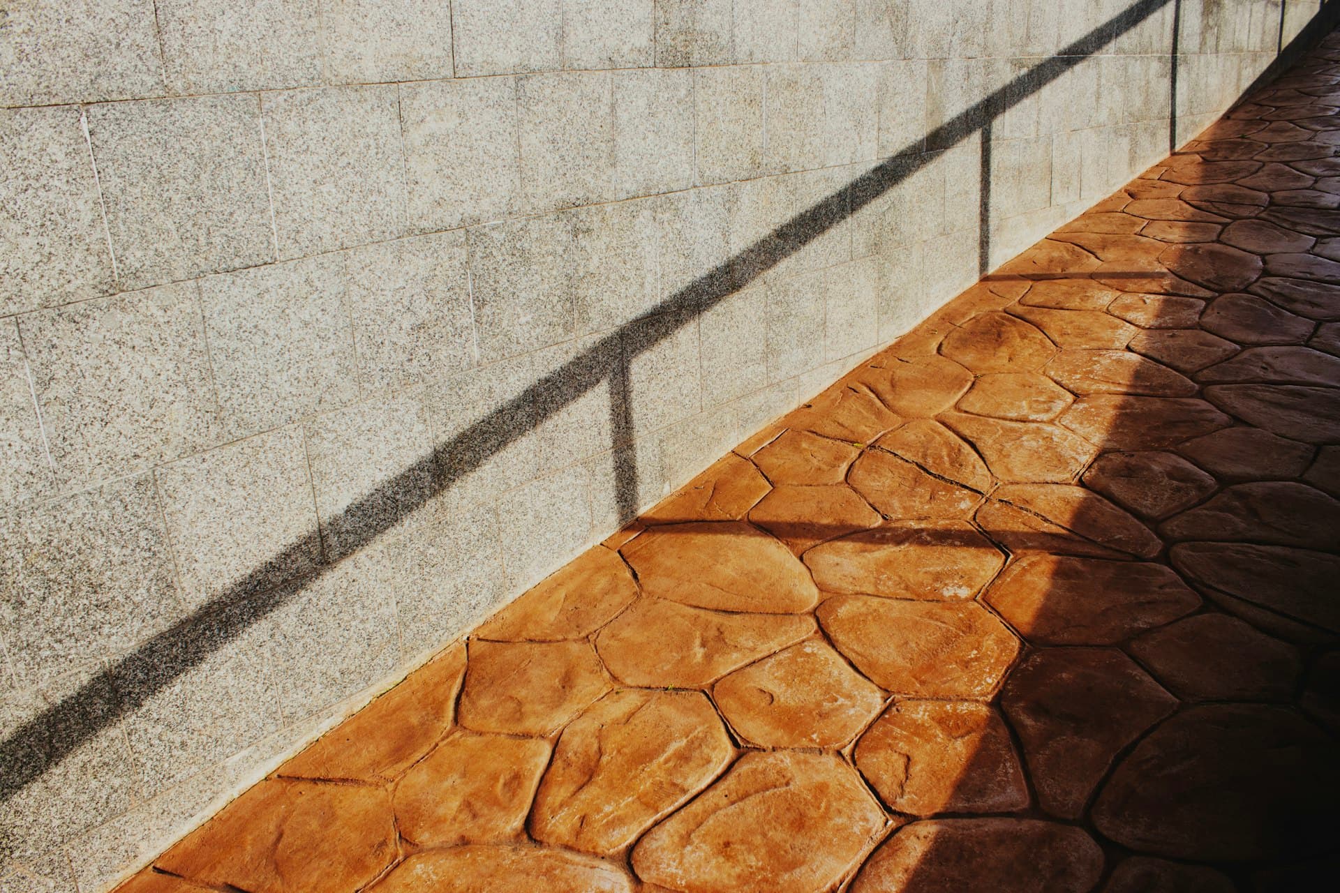 Sunlit stamped concrete walkway laid in a flagstone pattern