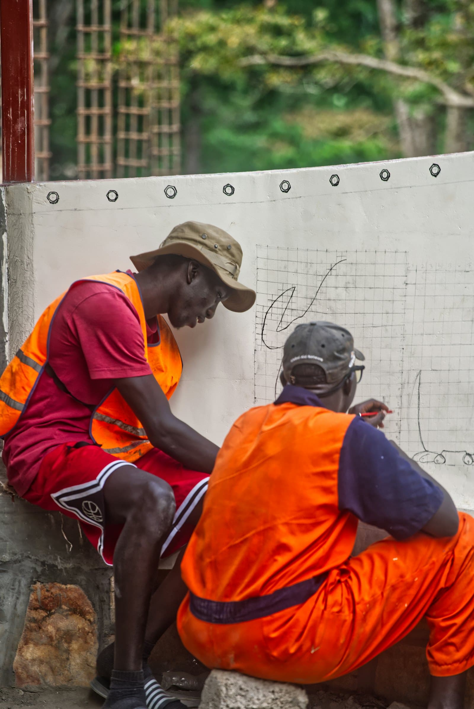 Two contractors in high-visibility vests reviewing project drawings on site