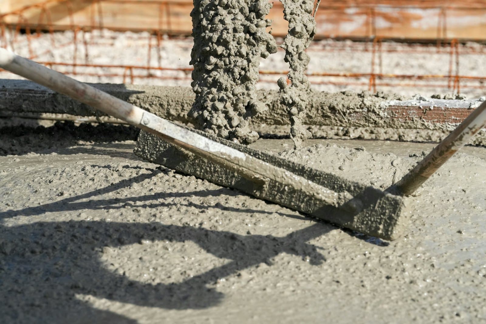 Fresh concrete being levelled with a screed across a new slab
