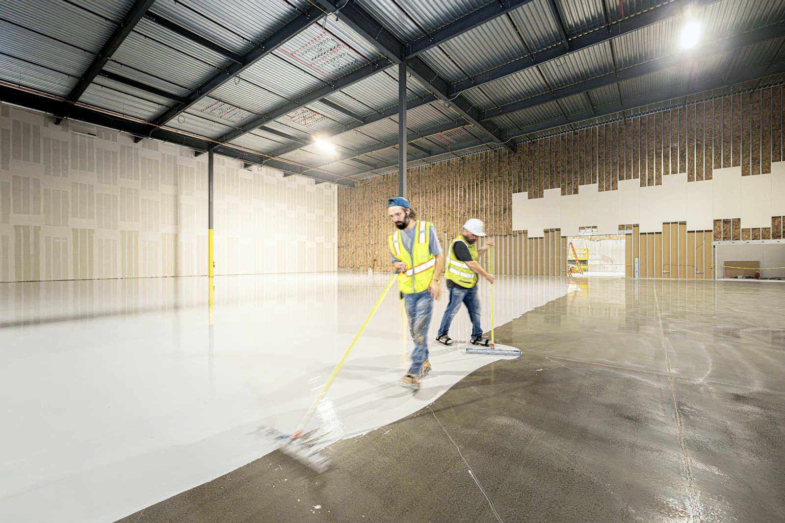 Crew applying a floor coating across a large slab
